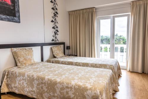 Una habitación de hotel con dos camas y una ventana. en Hotel Caldas Internacional, en Caldas da Rainha
