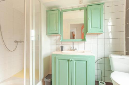 a green bathroom with a sink and a mirror at Beautiful house in nature for 20 people in Wetering