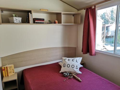 une petite chambre avec un lit avec une couverture rouge et une fenêtre dans l'établissement Feriendorf Le Tamerici Mobilehome Arno für 6 Personen, à Marina di Cecina