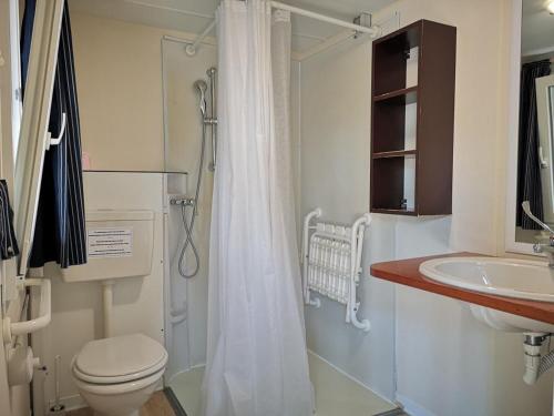 une salle de bains avec toilettes et lavabo dans l'établissement Feriendorf Le Tamerici Mobilehome Costa Rei für 6 Personen, à Marina di Cecina