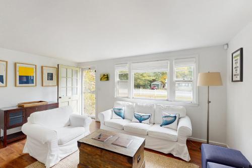 ein Wohnzimmer mit zwei weißen Stühlen und einem Tisch in der Unterkunft The Kettle Cottage in Cotuit