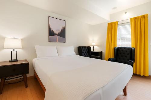 a bedroom with a large white bed and two chairs at Snowcreek Suite - Aspen - Hot Tub - Kitchenette in Leavenworth