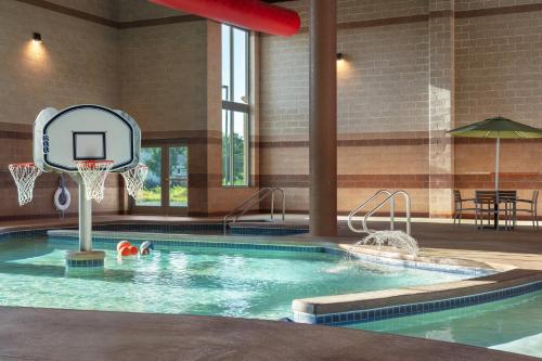 a pool with a basketball hoop and a person in the water at Holiday Inn Stevens Point - Convention Center by IHG in Stevens Point