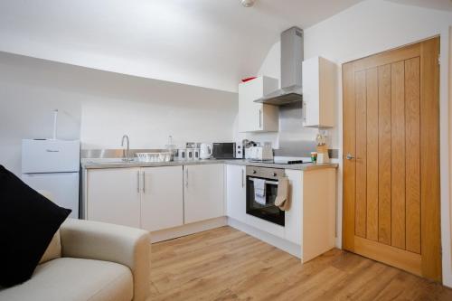 eine Küche mit weißen Schränken und einem Sofa in einem Zimmer in der Unterkunft Modern 1-BR Apartment near Cardiff City Centre in Cardiff
