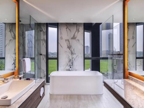 a bathroom with a large tub and a large window at Mercure Tangerang BSD City in Tangerang