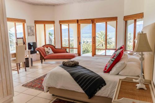 - une chambre avec un grand lit dans une pièce dotée de fenêtres dans l'établissement Barton Luxury Villas, à Botrivier