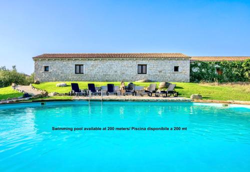 a pool with chairs and a house in the background at ISA - Apartments with common swimming-pool and outdoor private area in Badesi in Badesi