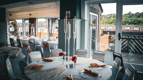 a dining room with tables and chairs and windows at Rivers Hotel in Newcastle upon Tyne