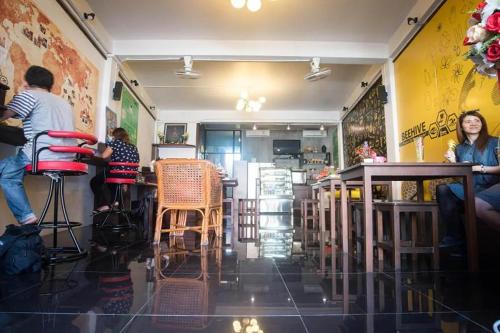 a group of people sitting at tables in a restaurant at Beehive Phuket Old Town Hostel in Phuket