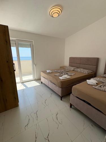 a bedroom with two beds and a large window at Apartmani Kula in Pečurice