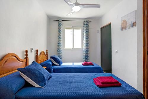two beds in a bedroom with blue sheets at Apartamento Azucenas in Conil de la Frontera