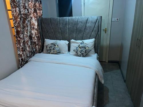 a bed with a gray headboard with pillows on it at Home sweet home in Nairobi