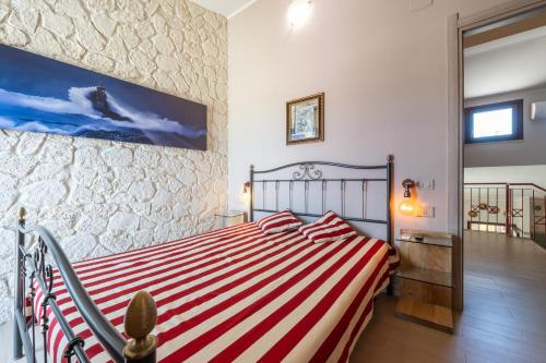 a bedroom with a bed with a red and white striped blanket at Il Nido di Mennenne in Villasimius