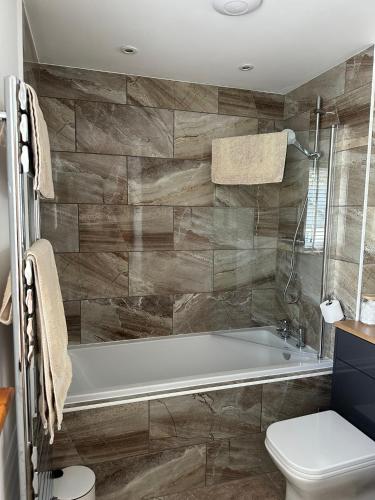 a bathroom with a tub and a toilet at Whitebridge Cottage in Swansea