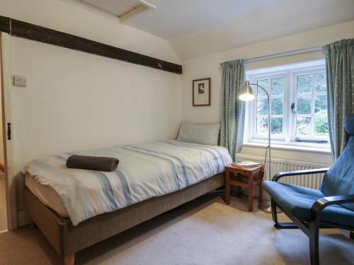 ein Schlafzimmer mit einem Bett und einem Stuhl und einem Fenster in der Unterkunft Cherry Cottage in Withyham