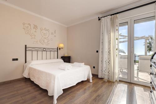 a white bedroom with a bed and a large window at Villa Alcaidesa Vistas al Mar in San Roque