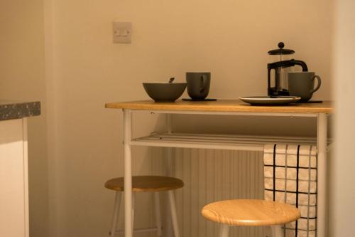 a table with two cups and two stools at Ballachulish - small double room nr Glencoe in Ballachulish