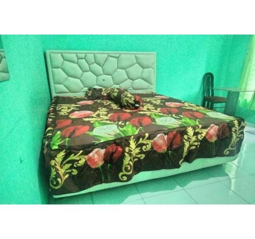 a bedroom with a bed with a floral bedspread at Hotel O Nany Asoka Syariah Near Anyong Cafe Studio in Medan