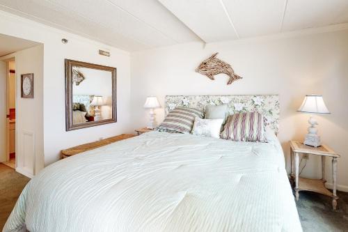 a bedroom with a large white bed and a mirror at Waikiki #302 in Ocean City