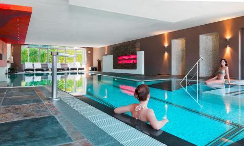 a swimming pool with two people in a hotel at Hotel Bütgenbacher Hof in Butgenbach