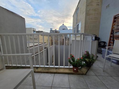 a balcony with a white fence and two plants at Best In Town in Qormi