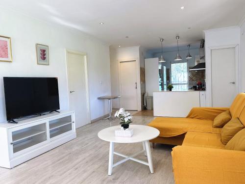 ein Wohnzimmer mit einer Couch, einem Fernseher und einem Tisch in der Unterkunft Sunshine Courtyard, Villa independiente en Valencia in Lliria