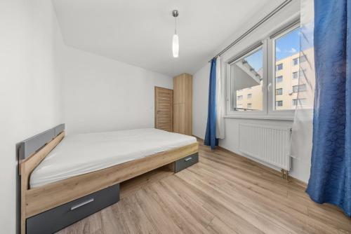 ein Schlafzimmer mit einem Bett und einem großen Fenster in der Unterkunft Air-conditioned 2-bedroom apartment, balcony, Závadská-Rača in Rača
