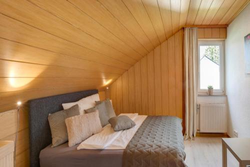 a bed in a room with a wooden ceiling at Ferienwohnung Am Schlehbach in Offingen