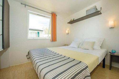 a bedroom with a large bed with a window at Camping Cœur de Vendée in La Boissière-de-Montaigu