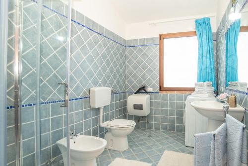 a blue tiled bathroom with a toilet and a sink at Luna in Onifai