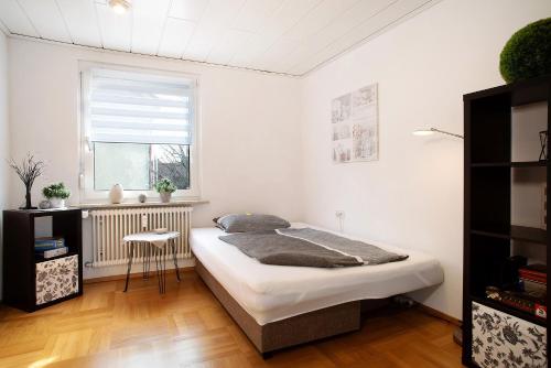 a white bedroom with a bed and a window at Bodensee Apartment Gresser in Meckenbeuren