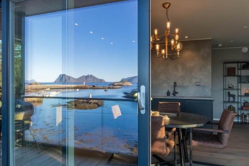 Un comedor con vista a un lago a través de una puerta de vidrio. en Lofoten Oceanfront Panoramic, en Kabelvåg