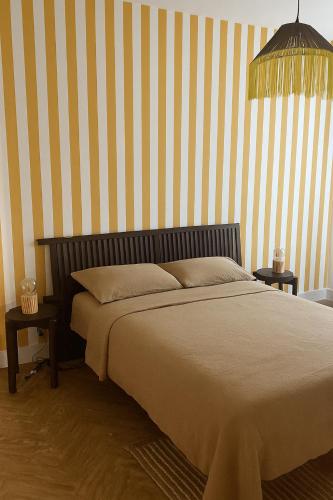 CommentryにあるGîte Minimalistの縞模様の壁とランプのある寝室のベッド