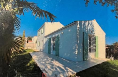 een wit huis met groene deuren en een palmboom bij Villa les Mésanges 5 min from the beaches in Vaux-sur-Mer