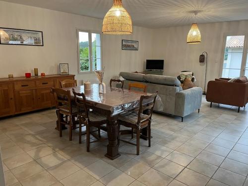 een woonkamer met een tafel, stoelen en een bank bij Villa les Mésanges 5 min from the beaches in Vaux-sur-Mer