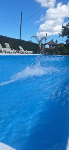 una piscina con agua azul y sillas blancas en Apart hotel Amter, en Fray Bentos