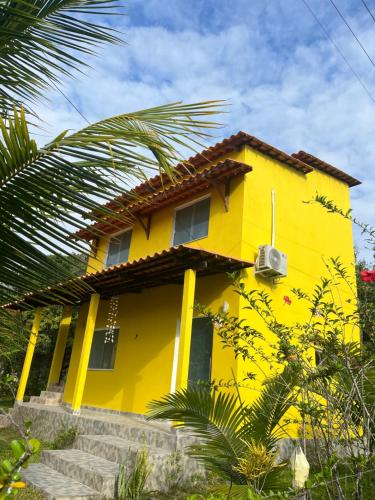 a yellow house with a palm tree in front of it at Ilha de Boipeba Casa com 2 quartos com ar condicionado no 1ºandar in Cayru