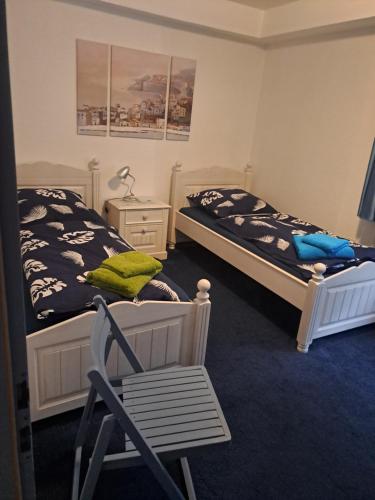 two beds in a room with a chair and a table at Praktisches Apartment für Monteure, Handwerker, Reisende in Wolfenbüttel