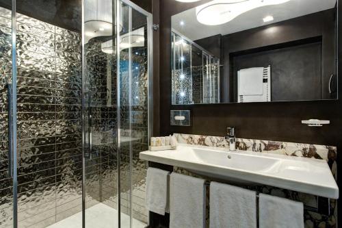uma casa de banho com um lavatório e uma cabina de duche em vidro. em Mascagni Luxury Rooms & Suites em Roma