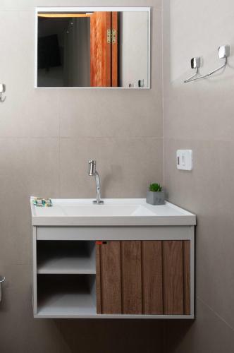 a bathroom with a white sink and a mirror at Pousada Uchimura in Itapecerica da Serra