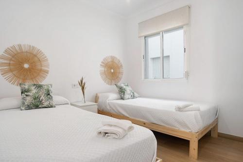 ein weißes Zimmer mit zwei Betten und einem Fenster in der Unterkunft Vazquez Mella Barbate in Barbate