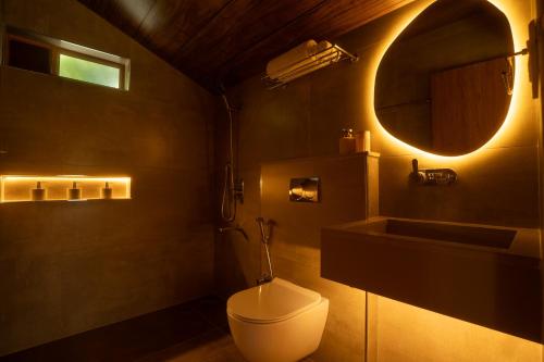 a bathroom with a toilet and a sink and a mirror at Vanantara - Riverside Eco Retreat in Ernakulam