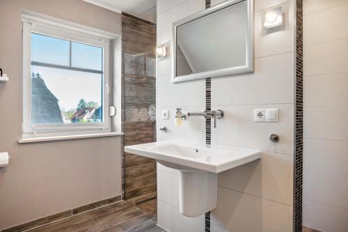 a white bathroom with a sink and a window at Reethaus Meerferien in Poseritz