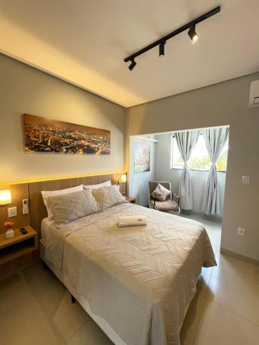 a bedroom with a large bed and a chair at Flat Executivo, Moderno e Aconchegante - Ahava Stays in Montes Claros