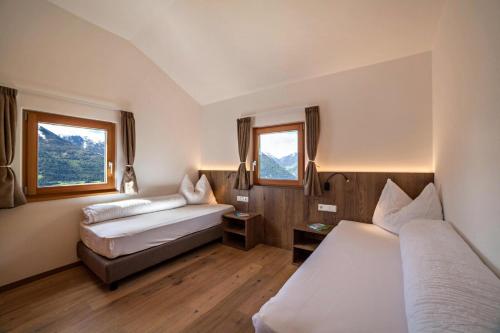 a hotel room with two beds and two windows at Flatschhof - Chalet Flatsch in Castelbello-ciardes