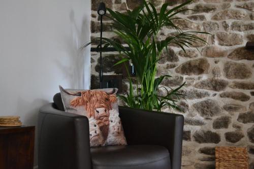 a black chair with a pillow in front of a stone wall at CherryBrook Wistman Suite in Two Bridges