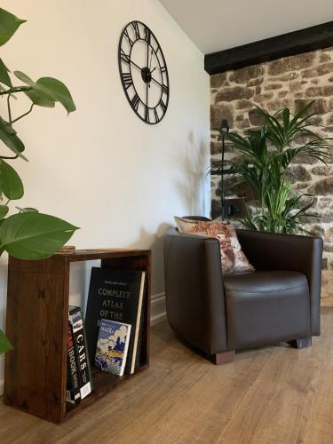 a living room with a chair and a clock on the wall at Delightful Dartmoor Apartment in Two Bridges