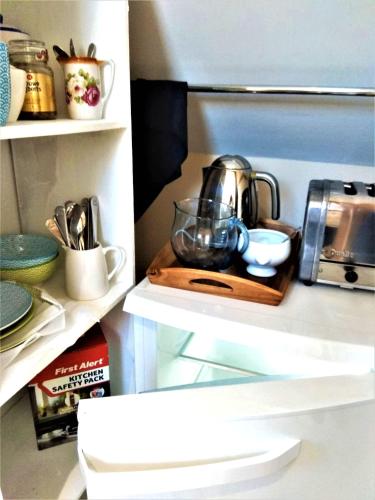 a tea kettle on a wooden tray in a refrigerator at Castle View Suite - Corvesgate Cottage - 3 room suite in Corfe Castle