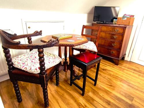 a dining room table with two chairs and a television at Castle View Suite - Corvesgate Cottage - 3 room suite in Corfe Castle