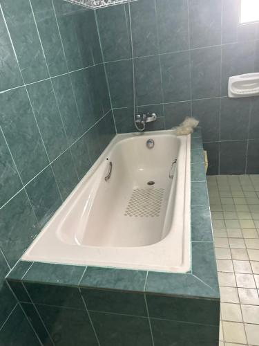 a bath tub in a bathroom with green tiles at RBNB by MELUSH in Cotonou